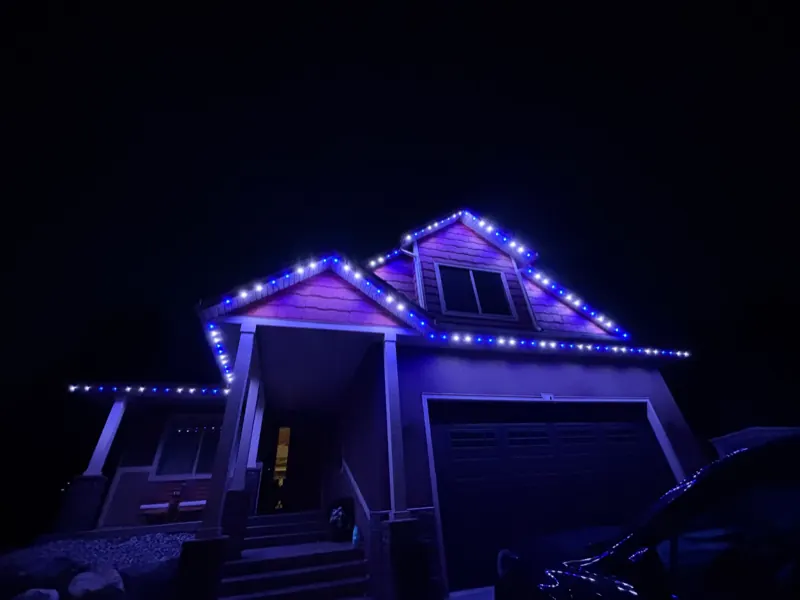 Permanent roofline lights in blue and white on a Castlegar BC home at night