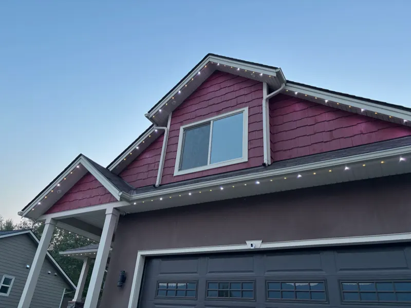 Low-profile permanent light track colour-matched to white trim on a Castlegar BC home in daylight