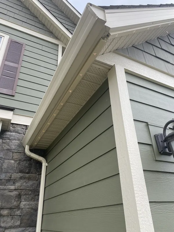 Close-up of low-profile permanent lighting track mounted flush under the eave of a Castlegar BC home, colour-matched to the trim