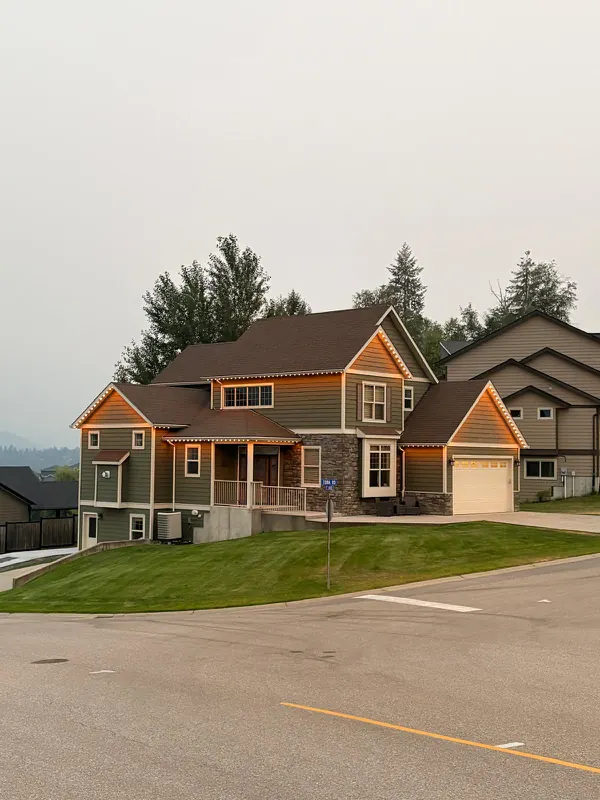 Warm white permanent roofline lighting switched on during the day on a large two-storey home in Castlegar BC